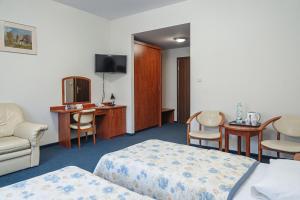クリニツァ・ズドルイにあるHotel Jaworzyna Krynickaのベッド2台、テーブルと椅子が備わるホテルルームです。