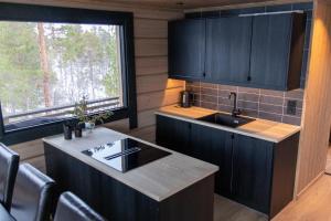 a kitchen with black cabinets and a sink and a window at Jutulhytta 