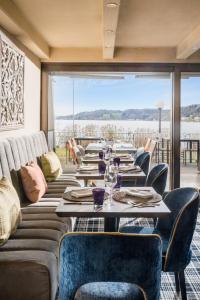 a dining room with tables and chairs and a large window at Strandhotel Schmerikon in Schmerikon