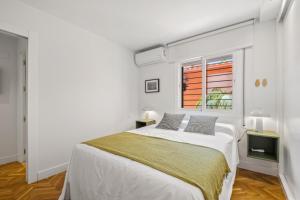 a white bedroom with a bed and a window at Mar de fondo en Pedregalejo in Málaga