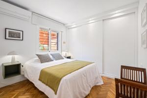 a white bedroom with a bed and a window at Mar de fondo en Pedregalejo in Málaga