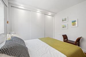 a white bedroom with a bed and a chair at Mar de fondo en Pedregalejo in Málaga