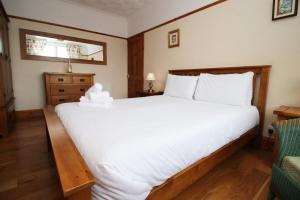 um quarto com uma grande cama branca e uma cadeira em Nessa’s Nook by Tŷ SA - Newport em Newport