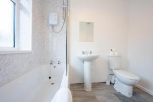 a white bathroom with a toilet and a sink at Clayton Street by Tŷ SA in Newport