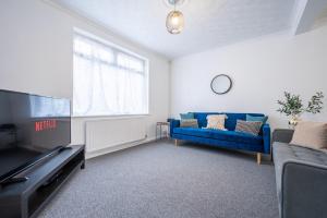 a living room with a blue couch and a tv at Clayton Street by Tŷ SA in Newport