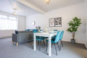 uma sala de jantar com uma mesa branca e cadeiras azuis em Clayton Street by Tŷ SA em Newport