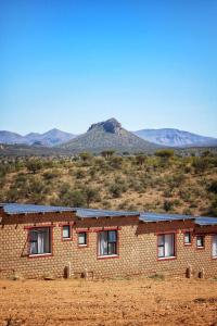 a brick building in the desert with mountains in the background at Valor Wellness Retreat in Windhoek
