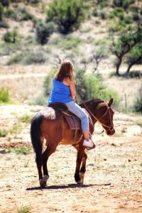 Młoda dziewczyna jeżdżąca konno po polnej drodze w obiekcie Valor Wellness Retreat w mieście Windhuk