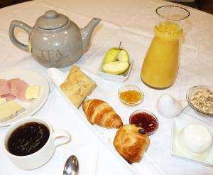 una mesa con una bandeja de alimentos para el desayuno y una tetera en Hostellerie Bon Pasteur, en Angers