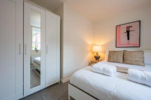 a white bedroom with a bed and a mirror at Close to Warwick University - Clover Way by Tŷ SA in Canley
