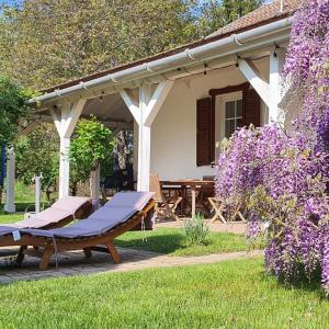 una mesa de picnic frente a una casa con flores púrpuras en Héthatár Wellness Vendégház - Fecskefészek, en Pusztavacs