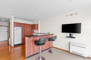 a kitchen with a bar with two stools and a flat screen tv at Metro Retreat - Auckland Central Apartment in Auckland