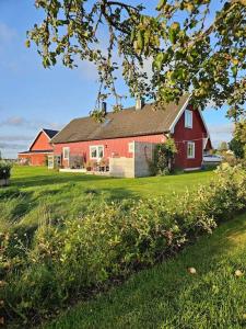 une grange rouge sur un champ verdoyant avec une maison dans l'établissement Gästhuset Sätuna, à Sätuna
