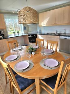 uma cozinha com uma mesa de madeira com pratos e copos de vinho em Gästhuset Sätuna em Sätuna
