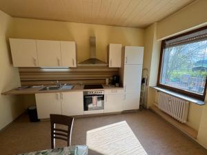 a kitchen with white cabinets and a table and a window at Schöne Wohnung mit Erker 
