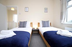 two beds with blue and white sheets in a room at Parkview by Tŷ SA - spacious 3 bed in Newport in Newport