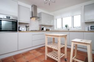 a kitchen with white cabinets and a wooden stool at Parkview by Tŷ SA - spacious 3 bed in Newport in Newport