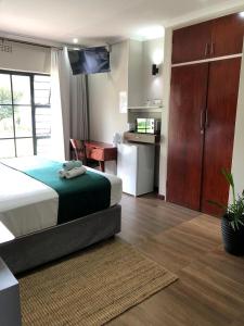 a bedroom with a bed and a desk and a kitchen at Serene Guesthouse in Middelburg