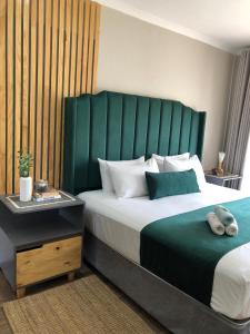 a bedroom with a large bed with a green headboard at Serene Guesthouse in Middelburg