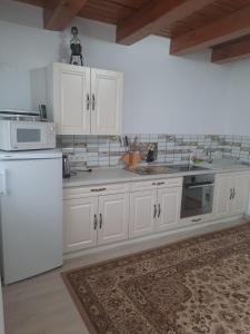 a kitchen with white cabinets and a white refrigerator at Cabanuta Dan & Alex in Cârțișoara