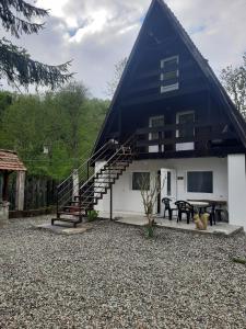 a house with a gambrel roof with a patio and stairs at Cabanuta Dan & Alex in Cârțișoara