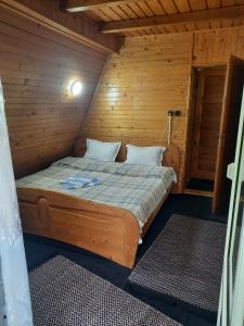 ein Schlafzimmer mit einem Bett in einem Holzzimmer in der Unterkunft Cabanuta Dan & Alex in Cîrţişoara