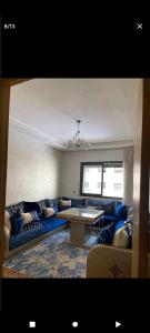 uma sala de estar com um sofá azul e uma mesa em اقامة ياسمين em Cité de Bournazel