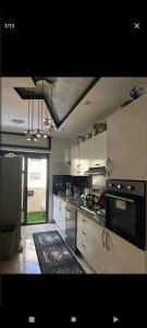 uma cozinha com armários brancos e um forno com placa de fogão em اقامة ياسمين em Cité de Bournazel