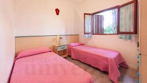 - 2 lits dans une petite chambre avec des draps roses dans l'établissement Bungalow Dancalia, à Eraclea Mare