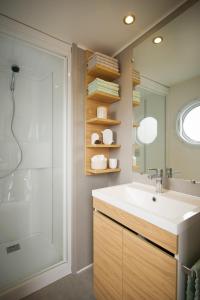 ein Badezimmer mit Waschbecken, Dusche und Spiegel in der Unterkunft Camping Aux Couleurs du ferret in Lège-Cap-Ferret + 76 Fotos