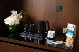 فندق الما ALMA Hotel في الرياض: طاولة غرفة في الفندق مع آلة صنع القهوة والزهور