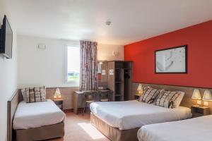 um quarto de hotel com duas camas e uma parede vermelha em Ace Hotel Troyes em Saint-André-les-Vergers