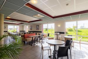 un ristorante con tavoli, sedie e finestre di Ace Hotel Troyes a Saint-André-les-Vergers
