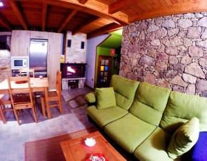 a living room with a green couch and a stone wall at Casa La Charca 