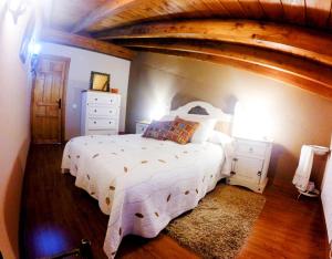 a bedroom with a white bed and a wooden ceiling at Casa La Charca 