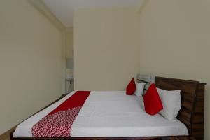 a bedroom with a bed with red and white pillows at OYO Flagship Prachi Guest House in Gorakhpur