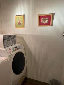 a washing machine in a bathroom with two pictures on the wall at Kiryu Ace Hotel in Kiryu