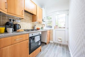uma cozinha com armários de madeira e um forno com placa de fogão em Dos Road by Tŷ SA em Newport