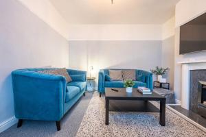 a living room with two blue couches and a coffee table at Dos Road by Tŷ SA in Newport