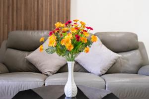 a vase of flowers on a table in front of a couch at Aparment Hà Đô Centrosa in Ho Chi Minh City