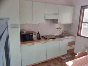 a kitchen with white cabinets and a microwave at Anna e Ale - mare e relax in Costa Rei +16 photos
