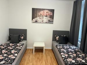 Zimmer mit 2 Betten und einem Tisch mit einer Blumenvase in der Unterkunft Elias 2 in Erfurt