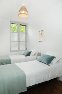 Cette chambre blanche dispose de 2 lits et d'une fenêtre. dans l'établissement Appartement Le Saint-Pierre by La Boîte En Plus, à Senlis