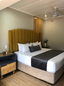 a bedroom with a large bed with a wooden headboard at Serene Guesthouse in Middelburg