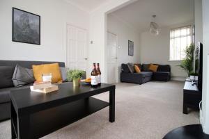 a living room with a couch and a table with wine bottles at Evansfield Close by Tŷ SA in Cardiff