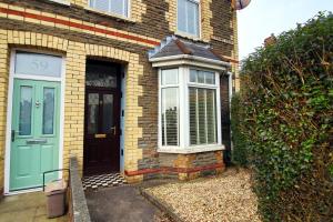 una puerta delantera de una casa de ladrillo con una puerta azul en Evansfield Close by Tŷ SA en Cardiff