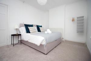 1 dormitorio con 1 cama grande con almohadas azules y blancas en Evansfield Close by Tŷ SA en Cardiff