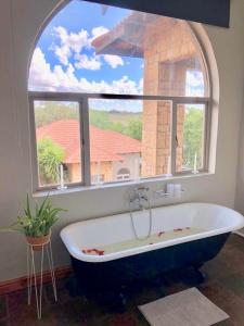 a bath tub in a bathroom with a large window at Blue Rain Guest House in Bloemfontein