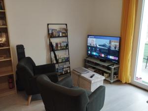 a living room with a flat screen tv and chairs at Le petit nid in Montgaillard