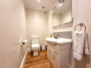 a white bathroom with a sink and a toilet at Min y Don Llandudno in Llandudno